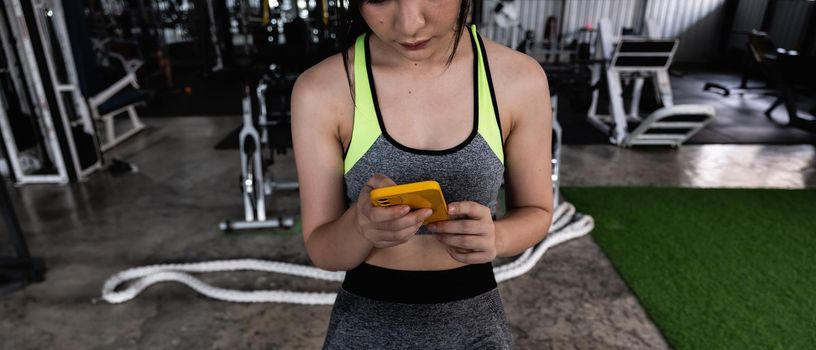 close up young fit woman using smart phone at gym.