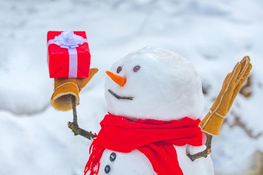 Snowman with shopping bag and gift on the white snow background. Greeting snowman. Merry Christmas and happy new year greeting card with copy-space