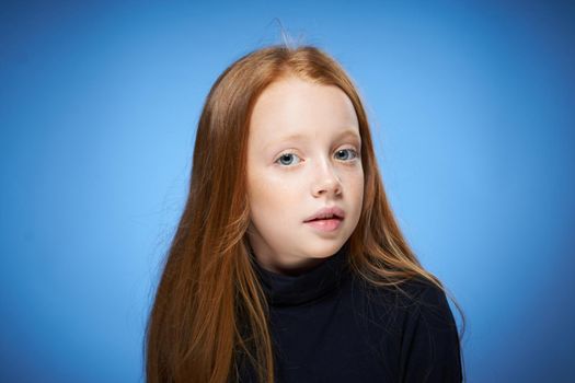 redhead girl with freckles on her face posing close-up blue background. High quality photo