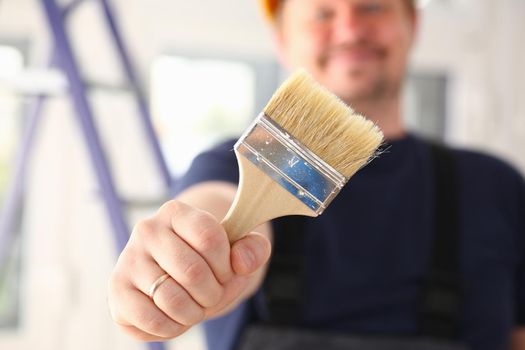 Arm of smiling worker hold brush closeup. Manual job workplace DIY inspiration improvement fix shop yellow helmet hard hat joinery startup idea industrial education profession career concept