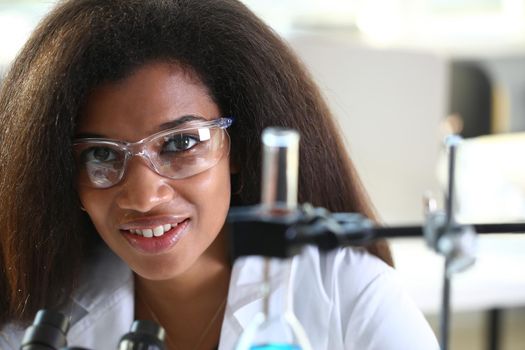Black female chemist student conducting research using a microscope for bacterial contamination of water searching for a vaccine to treat diseases in medicine doctor concept
