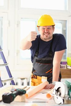 Smiling funny worker in yellow helmet posing. Manual job workplace DIY inspiration improvement fix shop hard hat joinery startup idea industrial education profession career concept