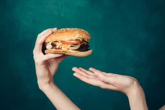 hamburger in hands close-up fast food green background. High quality photo