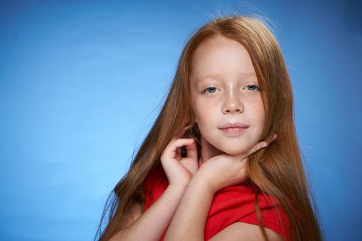 cute red-haired girl in red t-shirt emotions blue background. High quality photo