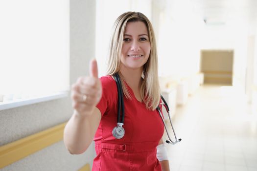 Young female doctor with stethoscope showing thumb up. Quality medical advice concept