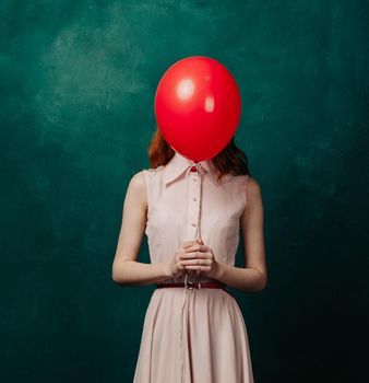 woman with red balloon on green background holiday fun. High quality photo