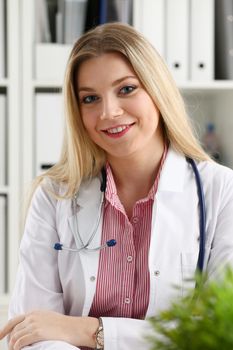 Beautiful smiling female doctor sit at workplace. Physical and disease prevention, patient aid, exam visit, 911, ward round, prescribe remedy, healthy lifestyle, consultant profession concept