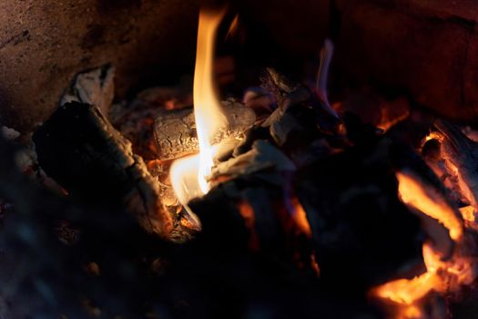 Burning black coals and fire bred in the fireplace. Close up