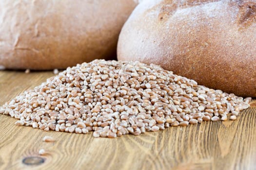 a few loaves of bread and a whole grain of wheat lying together on a wooden table