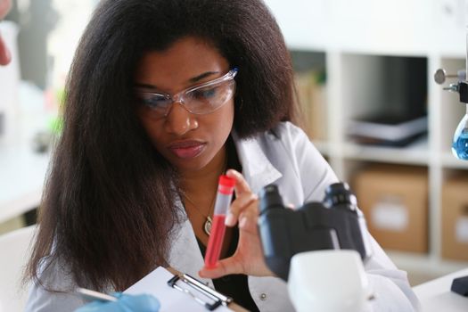 A female chemist holds test tube of glass in his hand overflows liquid solution potassium permanganate conducts an analysis reaction takes various versions reagents using chemical manufacturing.