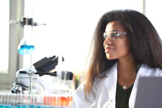 Black female chemist student conducting research using a microscope for bacterial contamination of water searching for a vaccine to treat diseases in medicine doctor concept