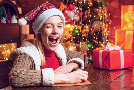 Eye winking blonde beautiful woman in Santa hat at Christmas home