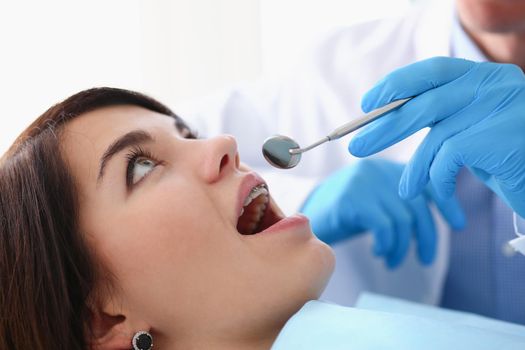 A woman at the reception of a male dentist examining teeth and oral cavity