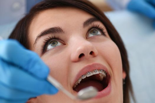 A woman at the reception of a male dentist examining teeth and oral cavity