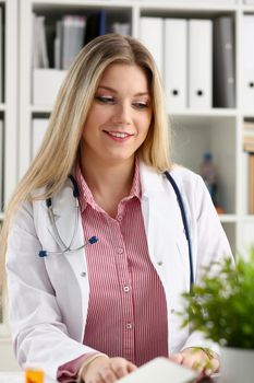 Beautiful smiling female doctor sit at workplace. Physical and disease prevention, patient aid, exam visit, 911, ward round, prescribe remedy, healthy lifestyle, consultant profession concept