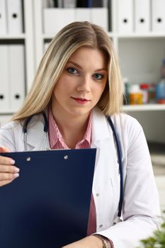 Beautiful smiling female doctor hold clipboard pad and fill something with silver pen. Physical illness prevention prescribe remedy ward round therapeutist assistance healthy lifestyle concept