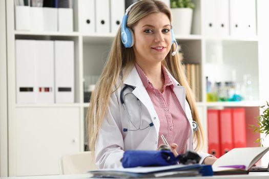 A beautiful feminine blonde doctor talking to patient over wireless headset advises a medical problem the formation of remote education internship callcenter specialist