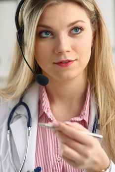 A beautiful feminine blonde doctor talking to patient over wireless headset advises a medical problem the formation of remote education internship callcenter specialist