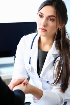 Young female doctor holds sick patient by hand expressing condolences and sympathy reports bad news about loss of loved ones due to cancer deadly aids disease and says we can handle support concept.