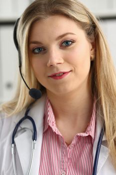 A beautiful feminine blonde doctor talking to patient over wireless headset advises a medical problem the formation of remote education internship callcenter specialist