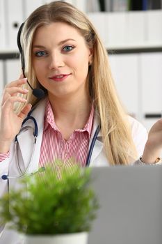 A beautiful feminine blonde doctor talking to patient over wireless headset advises a medical problem the formation of remote education internship callcenter specialist