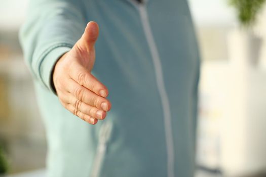 Man in sport suit and tie give hand as hello in office closeup. Friend welcome mediation offer, positive introduction thanks gesture summit participate approval motivation male arm strike bargain