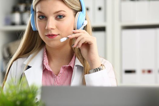 A beautiful feminine blonde doctor talking to patient over wireless headset advises a medical problem the formation of remote education internship callcenter specialist