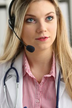 A beautiful feminine blonde doctor talking to patient over wireless headset advises a medical problem the formation of remote education internship callcenter specialist