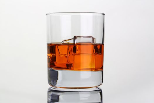 Whiskey with ice in glass beaker on gray background