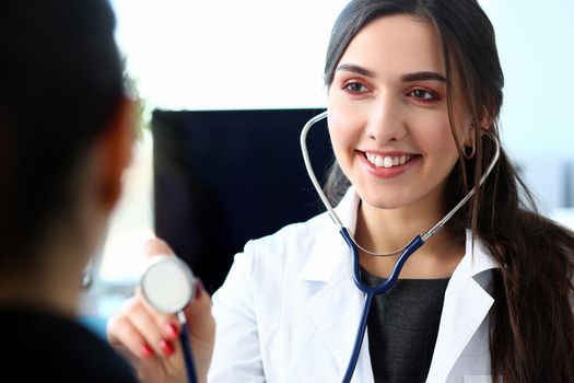 Portrait beautiful smiling female doctor hold in arm stethoscope head going to listen patient. Tool shop or store physical disease prevention er consultant 911 pulse measure healthy lifestyle concept