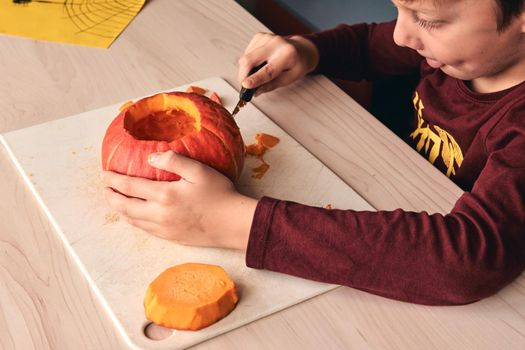 Halloween, decoration and holidays ideas- close up of kid with knife carving pumpkin or jack-o-lantern. 6 years boy has homefamily fun activity. Mom spending time with son together.