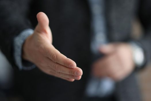 Businessman in suit stretching out his hand for handshake with partner closeup. Profitable deals and projects in business concept