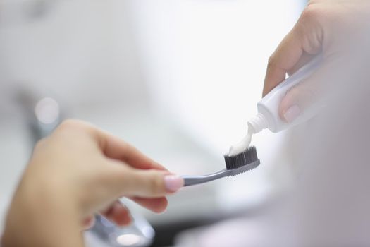 Female hands squeezing toothpaste onto brush in bathroom closeup. Daily oral hygiene concept