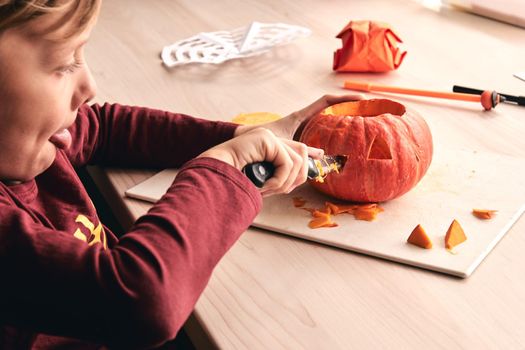 Halloween, decoration and holidays ideas- close up of kid with knife carving pumpkin or jack-o-lantern. 6 years boy has homefamily fun activity. Mom spending time with son together.