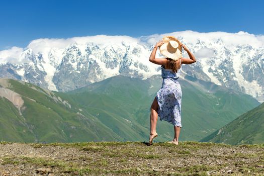 Young beautiful girl on the edge of a cliff looks at a beautiful mountain landscape, Incredible views of the Caucasus Mountains, Ushguli, Georgia, Caucasus,