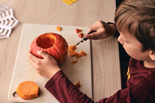 Halloween, decoration and holidays ideas- close up of kid with knife carving pumpkin or jack-o-lantern. 6 years boy has homefamily fun activity. Mom spending time with son together.