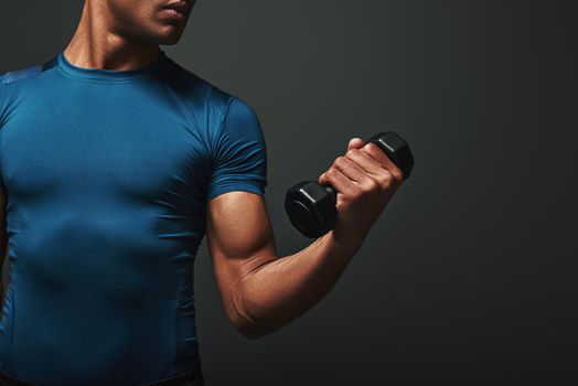 Sport, bodybuilding, fitness and people concept. Man with dumbbells flexing muscles isolated on dark background. Close up