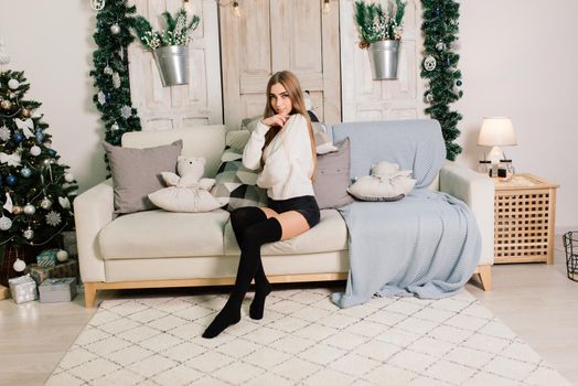 Happy young lady with long hair near fireplace and the Christmas tree, gifts. New year concept.