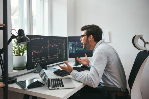No way Shocked young businessman or trader in formalwear is shouting and gesturing while looking at trading charts and financial data in the office. Stock exchange. Financial trading concept. Investment concept. Forex market