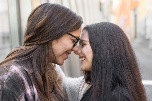 Young affectionate lesbian couple standing outdoors in city. High quality photo.
