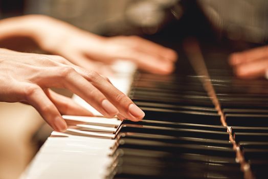 Beautiful Piano Melody...Close up view of female hands playing on piano her favorite classical music. Musical instrument. Music education. Piano keyboard