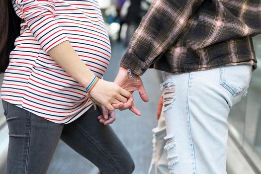 Close up of Unrecognizable Lesbian Pregnant Couple holding hands outdoors. High quality photo