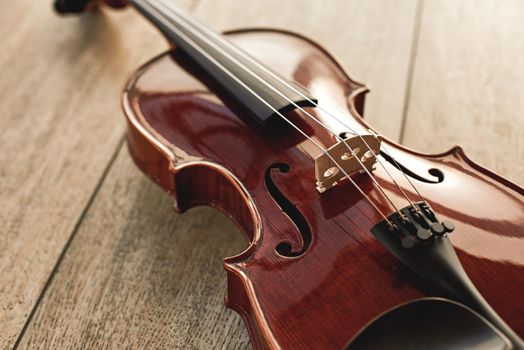 Close up view of beautiful classical violin lying on wooden background. Musical instruments. Music equipment. Music background