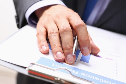 Male hands hold documents with financial statistics at office workspace closeup. White collar check money papers stock exchange market internal Revenue Service inspector earning list concept