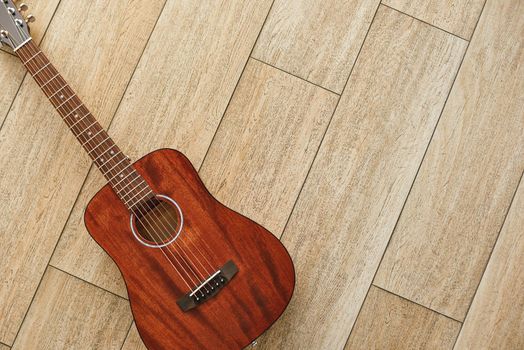 Beauty of musical instrument. Top view of the brown acoustic guitar lying on the wooden floor. Music background. Music concept. Musical instruments