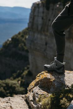 Hiking shoe of a woman stepping on a small rock with mointain background on sunny day. Copy space