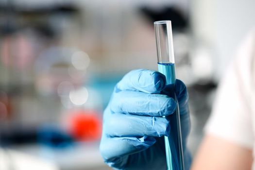 A male chemist holds test tube of glass in his hand overflows a liquid solution of potassium permanganate conducts an analysis reaction takes various versions of reagents using chemical manufacturing.