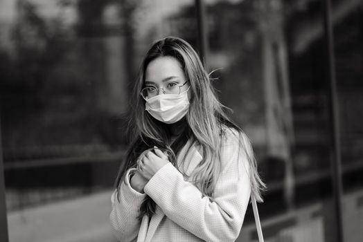 Young asian woman wearing face mask is standing at a domestic street.