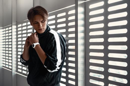 Young sportive man runner posing near window. He looks to the right, cool temper