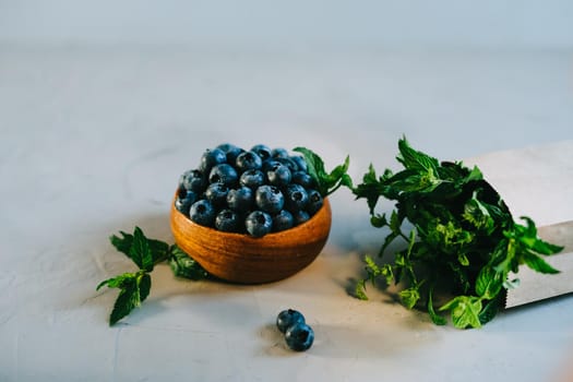Wooden bowl with delicious blueberries. Environmentally friendly packaging and utensils. A bowl of healthy berries kraft bag with fresh mint. The concept of healthy eating and nutrition.